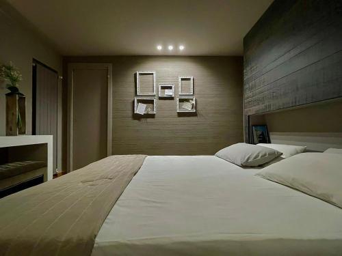 a large white bed in a bedroom with pictures on the wall at Luxury Artistic & Design Apartment in Historic Center, with Chromotherapy & Private Parking, Navigli - Bocconi in Milan