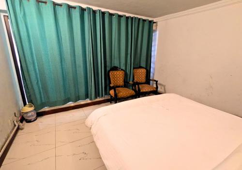 a bedroom with two chairs and a bed and a window at Grand Heights Hotel in Murree