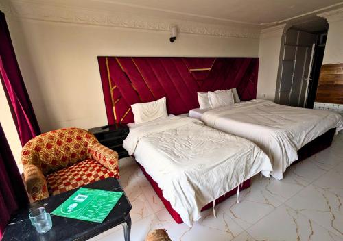 a hotel room with two beds and a chair at Grand Heights Hotel in Murree