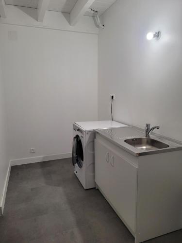 a kitchen with a washing machine and a sink at Les écuries in Secondigny