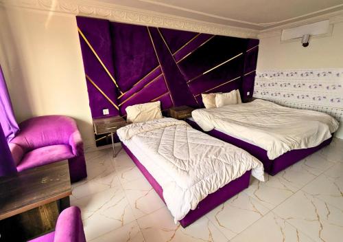 a hotel room with two beds and a chair at Grand Heights Hotel in Murree