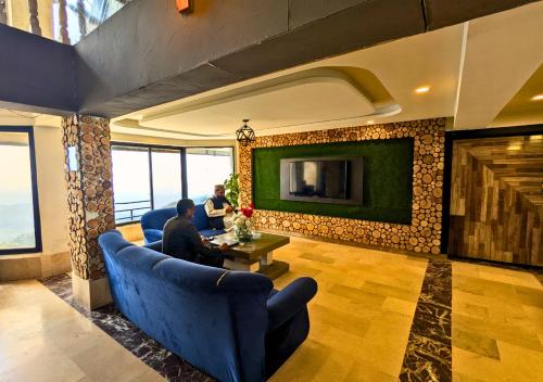 two people sitting in a living room with a fireplace at Grand Heights Hotel in Murree