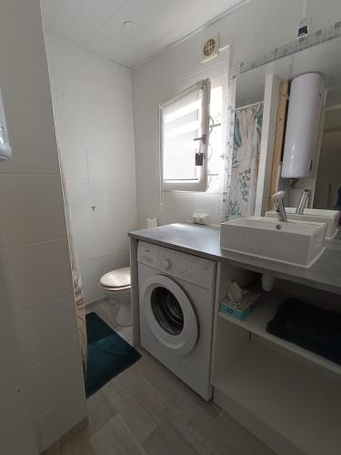 une salle de bain avec une machine à laver et un lavabo dans l'établissement Le Charly, au Barcarès