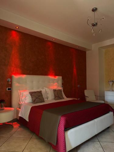 Hotel Il Giardino degli Aranci في نولا: غرفة نوم مع سرير كبير مع أضواء حمراء على الحائط