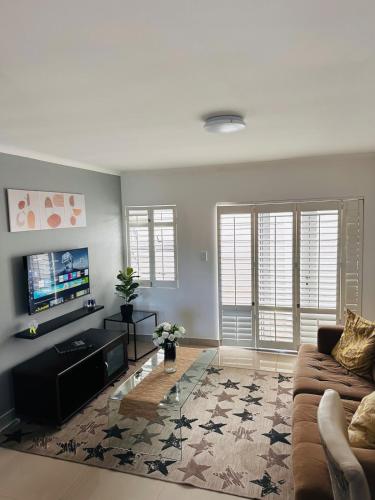 Una sala de estar con un sofá y un televisor de pantalla plana. en Cozy Retreat with a Pool!, en Cape Town