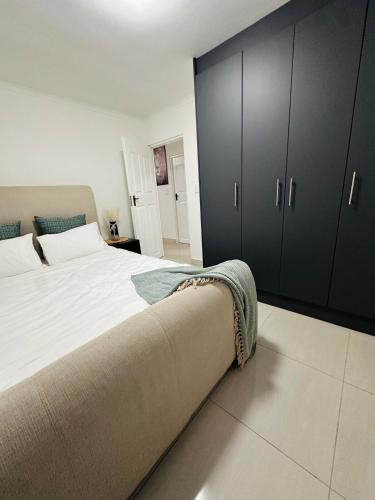 Un dormitorio con una cama grande con armarios negros. en Cozy Retreat with a Pool!, en Cape Town