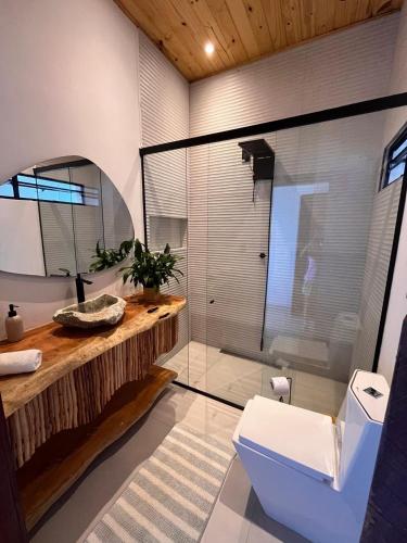 a bathroom with a toilet and a glass shower at Casa Amar Pipa in Pipa
