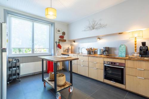 une cuisine avec une table au milieu dans l'établissement Cozy Breizh -4 ch 8 pers- 1km plage, à Penmarcʼh