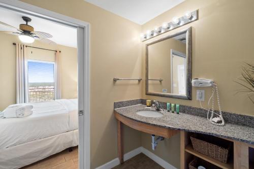 un bagno con un lavandino, un letto e uno specchio di Splash Beach Resort #1503-E by Book That Condo a Panama City Beach
