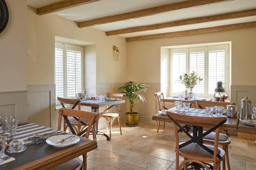 a dining room with tables and chairs and windows at Rockstone Cottage in Freshwater