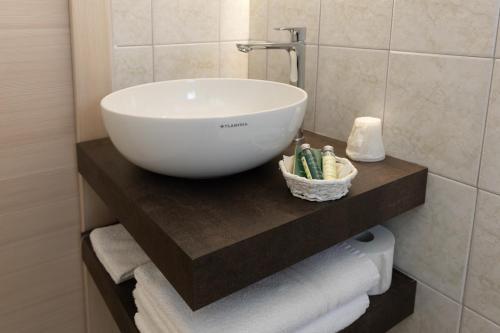 a white bowl sink on a shelf in a bathroom at Albergo Venezia in Passo Rolle