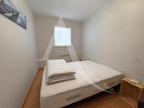 une chambre avec un lit avec des draps blancs et une fenêtre dans l'établissement APPARTEMENT EN RDC, 2 CHAMBRES, RES AVEC PISCINE, QUARTIER PORT DE SETE, à Sète