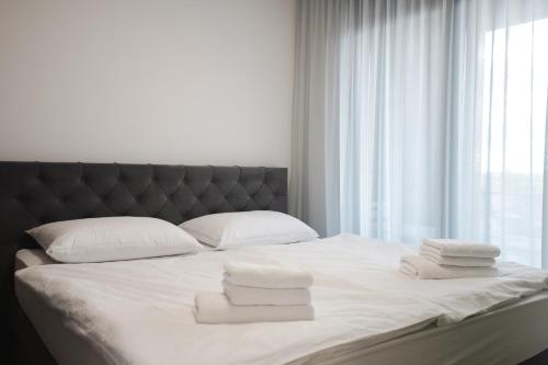 ein Bett mit weißen Handtüchern und einem Fenster in der Unterkunft FOUR Seasons by DISTRICT in Osijek