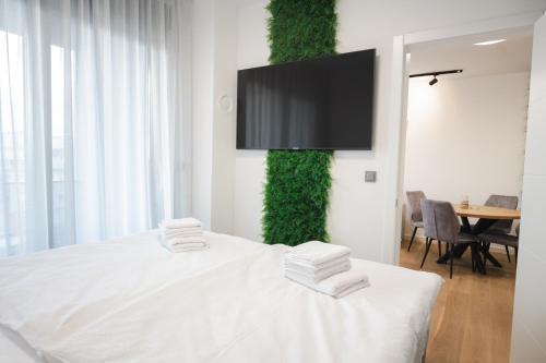 Schlafzimmer mit einem weißen Bett und einem TV an der Wand in der Unterkunft FOUR Seasons by DISTRICT in Osijek
