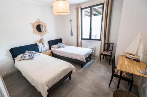 Cette chambre comprend 2 lits, une table et un miroir. dans l'établissement Villa classée 5 étoiles 200m de la plage piscine chauffée 5 vélos, à Capbreton