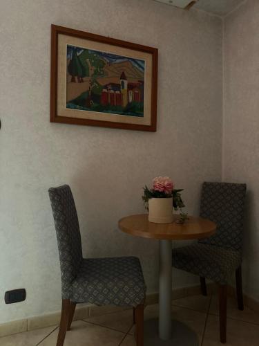 a table with two chairs and a painting on the wall at Hotel Il Giardino degli Aranci in Nola