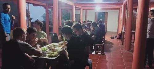 a group of people sitting at a table eating food at Long Chieu homestay in Hoàng Su Phì