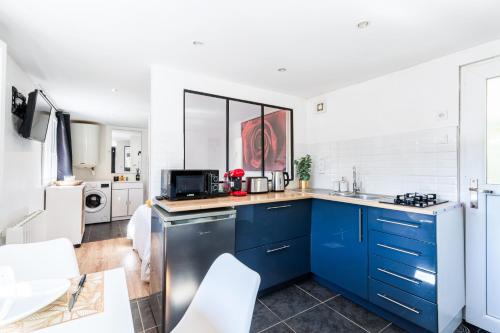 La cuisine est équipée de placards bleus et d'un réfrigérateur blanc. dans l'établissement Appartement - Parking Gratuit - La Baule - Cuisine - Wifi - Calme, à Pornichet