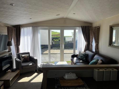 un soggiorno con un divano e una grande finestra di Static Caravan on the Jurassic Coast at Freshwater Beach Holiday Park a Burton Bradstock