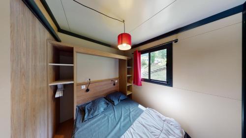 une petite chambre avec un lit et une fenêtre dans l'établissement Camping la Pommeraie, à Vic-sur-Cère