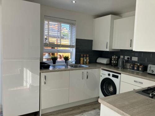 a white kitchen with a sink and a dishwasher at Sheffield 3-Bed Warm Comfy home in Orgreave