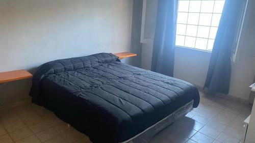 a bed with a blue comforter in a bedroom at Casa a 3 cuadras del centro in San Rafael