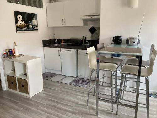 une cuisine avec des armoires blanches et une table et des chaises dans l'établissement Bright and airy apartment for 2 guests near Marché Provencal, à Antibes