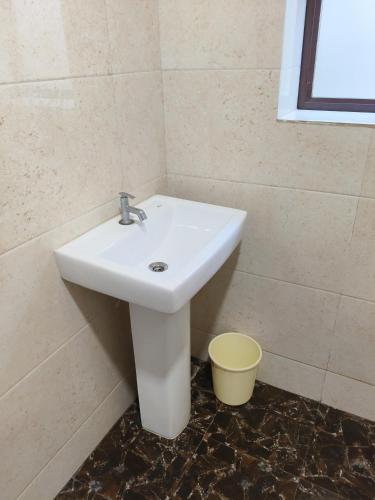 a bathroom with a white sink and a bucket at Sri Rameshwar Paradise in Rāmnagar