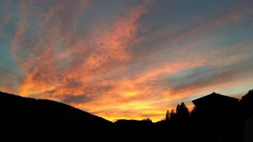 a sunset in the sky over a mountain at Außermoos-Zuhaus in Alpbach