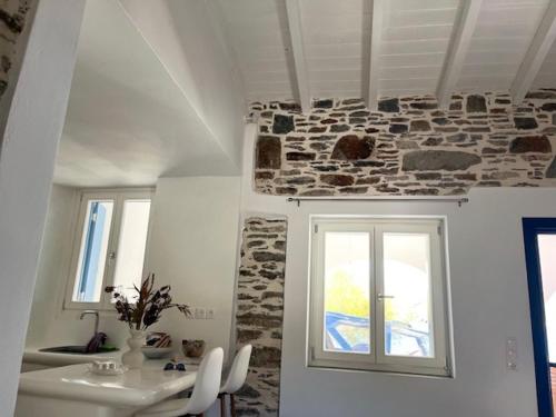 a room with a table and a stone wall at Ankon Beach House Kythnos in Kithnos