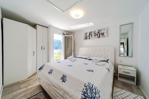 a white bedroom with a bed and a window at Seaside Holiday Home Ema in Vela Luka