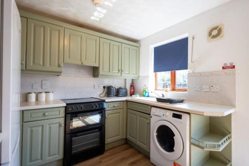 a kitchen with green cabinets and a washer and dryer at Eastwood in Colchester