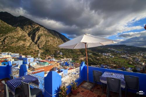 a balcony with a table and an umbrella at Casa Sanae in Chefchaouene
