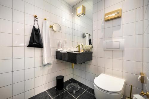 un bagno piastrellato bianco con servizi igienici e lavandino di Radisson Hotel Papirfabrikken Silkeborg a Silkeborg