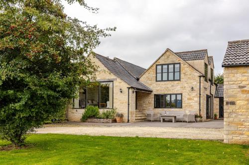 a stone house with a patio in front of it at Spacious farmhouse with stunning valley views in Woodchester