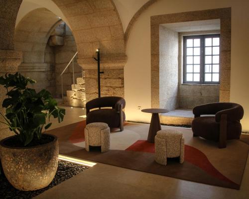 a living room with two chairs and a potted plant at MS Collection Arouca - Mosteiro de Arouca in Arouca
