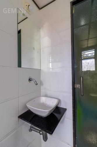 a white bathroom with a sink and a mirror at Hotel Gemini in Mumbai
