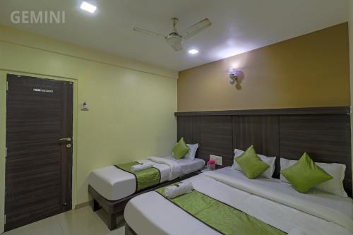 two beds in a room with green pillows at Hotel Gemini in Mumbai