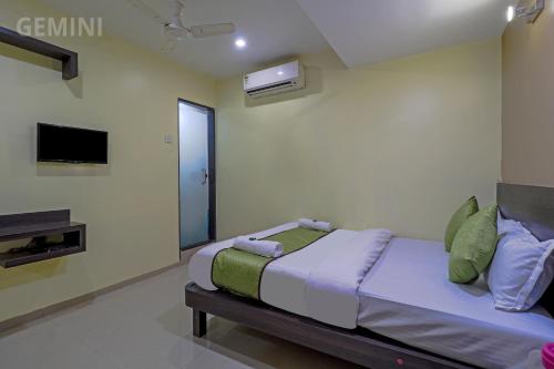 a bedroom with a bed and a tv on the wall at Hotel Gemini in Mumbai