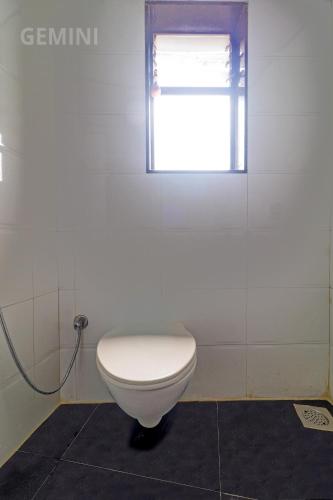 a white toilet in a bathroom with a window at Hotel Gemini in Mumbai