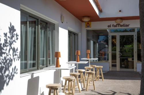 a row of tables and stools in front of a building at Casual Bahía Ibiza in San Antonio Bay