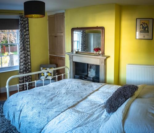 a bedroom with a bed with a fireplace and a mirror at Wirksworth Townhouse - full of character in Wirksworth