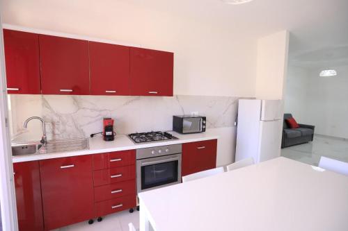 a kitchen with red cabinets and a stove top oven at Clara Apartment in Parghelia