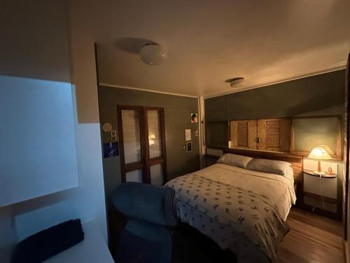 a bedroom with a bed and a blue chair at Casa Rover - Floripa in Florianópolis