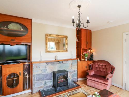a living room with a stone fireplace and a chair at Teach Ards in Kilgarvan