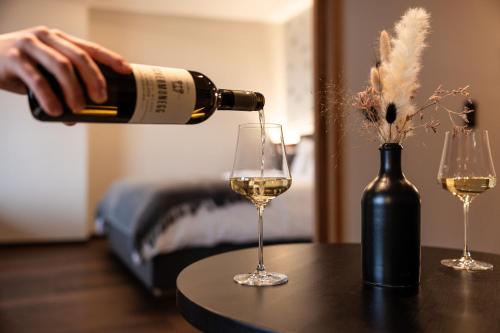 a person pouring white wine into two wine glasses at Wohnen beim Wein Tschermonegg in Sulz