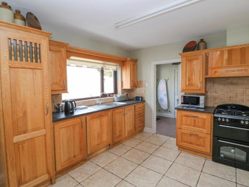 a kitchen with wooden cabinets and a sink and a stove at Teach Ards in Kilgarvan