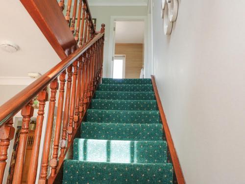 a staircase with green carpet and wooden railings at Teach Ards in Kilgarvan