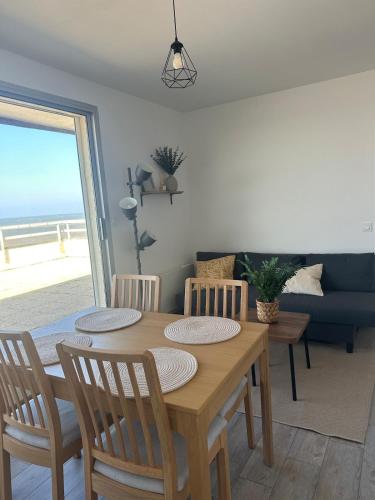 Un comedor con una mesa y sillas y un sofá. en L'echappee Marine - Vu Mer, en Courseulles-sur-Mer