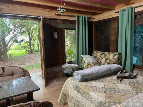 a room with a bed and chairs and a window at Choupana das Araucárias in Sapiranga